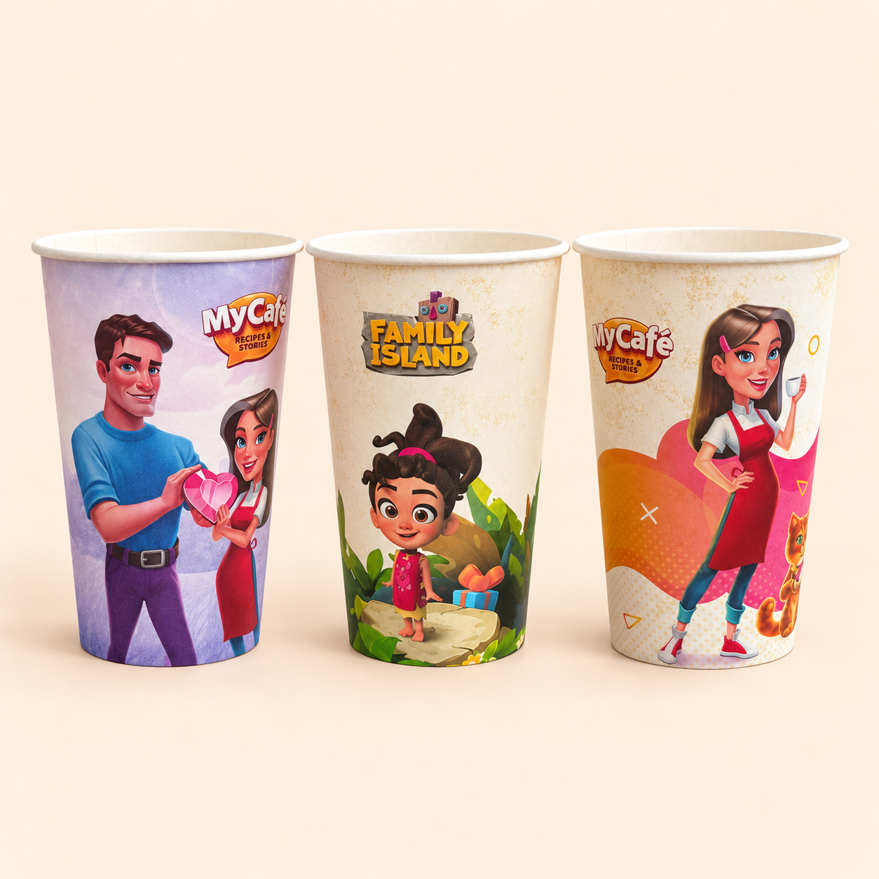 Trys spalvingi popieriniai puodeliai su „My Café“ ir „Family Island“ dizainais kreminiame fone